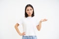 So what. Young asian woman shrugs shoulds, looks questioned at camera, cant understand, stands over white background