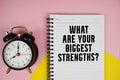 What Are Your Biggest Strengths? text written on notepad with alarm clock on pink background Royalty Free Stock Photo