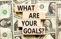 What are your goals symbol. Concept words What are your goals on wooden blocks. Beautiful background from dollar bills. Business,