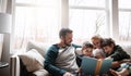 Whats family time without a story to share. two adorable brothers reading a book together with their parents while Royalty Free Stock Photo