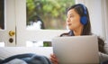 Whats the weekend without a side of wifi. an attractive young woman wearing headphones while using a laptop at home. Royalty Free Stock Photo