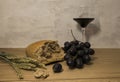 A wheat bread and red grapes with wine