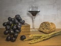 A wheat bread and red grapes with wine