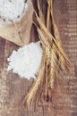 Wheat ears and flour sack on wooden background