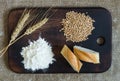 Wheat ears, grains, flour and sliced bread on a kitchen board on a sacking background Royalty Free Stock Photo