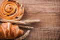 Wheat ears raisin bun croissant on oak wooden Royalty Free Stock Photo