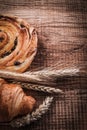 Wheat ears raisin roll tasty croissant on oak wooden board food Royalty Free Stock Photo