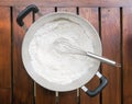 Wheat flour and whisk in the pan on wood background Royalty Free Stock Photo