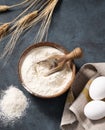 Wheat flour in a wooden bowl with a scoop and eggs on a dark background. Natural organic flour for home baking Royalty Free Stock Photo