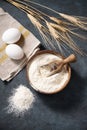 Wheat flour in a wooden bowl with a scoop and eggs on a dark background. Natural organic flour for home baking Royalty Free Stock Photo