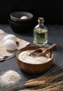 Wheat flour in a wooden bowl with a scoop, eggs and oil on a dark background Royalty Free Stock Photo