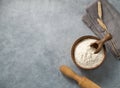 Wheat flour in a wooden bowl with a scoop and rolling pin on a blue background. Natural organic flour for home baking Royalty Free Stock Photo