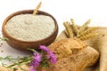 Wheat grains in wooden bowl, wheat ears and Wholemeal wheat flour in ceramic bowl, wheat ears, homemade bread and cornflowers