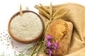 Wheat grains in wooden bowl, wheat ears and Wholemeal wheat flour in ceramic bowl, wheat ears, homemade bread and cornflowers