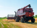 Wheat harvesting in the summer. Red harvester working in the field. Golden ripe wheat harvest agricultural machine harvester on