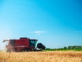 Wheat harvesting in the summer. Red harvester working in the field. Golden ripe wheat harvest agricultural machine harvester on