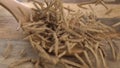 Wheat rye bran flakes sticks fall on a wooden spoon in slow motion. On a rustic wood surface