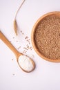 Wheat seeds grains in wooden bowl near with flour in spoon spatula with heap of grains and with ear of wheat, top view Royalty Free Stock Photo