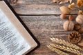 Wheat stalks, nuts, and autumn leaves with open holy bible Psalm 65 on wooden table, top view