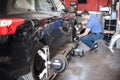 Wheel alignment. Car mechanic installing sensor during suspension adjustment Royalty Free Stock Photo