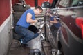 Wheel alignment. Car mechanic installing sensor during suspension adjustment Royalty Free Stock Photo