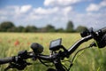 Wheel from the bike with navigation devices on the background of a spring rye field with red poppies. In the distance, there is a
