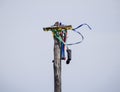 wheel of a cart hung on a pillar. Multicolored ribbons and boots hang on a wooden post