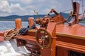 A wheel and deck of a wooden old sailing yacht against the background of the sea and the blue sky Royalty Free Stock Photo