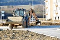 Wheel excavator works on ground shaping in front of the flathouse