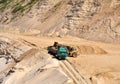 Wheel front-end loader loading sand into heavy dump truck at the opencast mining quarry. Dump truck transports sand in open pit Royalty Free Stock Photo
