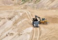 Wheel front-end loader loading sand into heavy dump truck at the opencast mining quarry. Dump truck transports sand in open pit Royalty Free Stock Photo