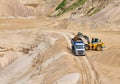 Wheel front-end loader loading sand into heavy dump truck at the opencast mining quarry. Dump truck transports sand in open pit Royalty Free Stock Photo