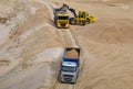 Wheel front-end loader loading sand into heavy dump truck at the opencast mining quarry. Dump truck transports sand in open pit Royalty Free Stock Photo