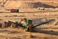 Wheel front-end loader loads sand into jaw crusher. Heavy machinery in the mining quarry, excavators and trucks. Mobile jaw Royalty Free Stock Photo