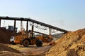 Wheel front-end loader unloading sand into heavy dump truck. Crushing factory, machines and equipment for crushing, grinding stone Royalty Free Stock Photo