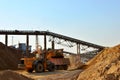 Wheel front-end loader unloading sand into heavy dump truck. Crushing factory, machines and equipment for crushing, grinding stone Royalty Free Stock Photo