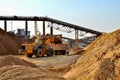 Wheel front-end loader unloading sand into heavy dump truck. Crushing factory, machines and equipment for crushing, grinding stone Royalty Free Stock Photo