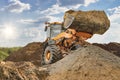Wheel front loader bulldozer pours sand. Distributes sand for road construction. Powerful earthmoving equipment. Construction site Royalty Free Stock Photo