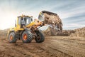 Wheel front loader bulldozer pours sand. Distributes sand for road construction. Powerful earthmoving equipment. Construction site Royalty Free Stock Photo