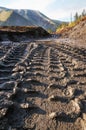 Wheel imprint from a wheel loader on a wet dirt road in a mountainous area