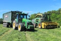 The wheel John Deere 8335R tractor with the trailer and the fodder harvesting John Deere 7450 combine Royalty Free Stock Photo