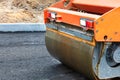 The wheel of a large road vibratory roller compacts fresh asphalt on the new road