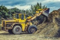 Wheel loader Excavator with backhoe unloading sand at eathmoving works in construction site quarry Royalty Free Stock Photo