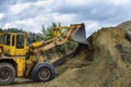 Wheel loader Excavator with backhoe unloading sand at eathmoving works in construction site quarry Royalty Free Stock Photo