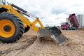 Wheel loader excavator machine wih multi-purpose bucket levelling construction site during earthmoving works Royalty Free Stock Photo