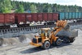 Wheel loader loads gravel into a dump truck at a cargo railway station.