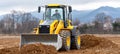 Wheel loader moving soil on construction site with mountains in background Royalty Free Stock Photo