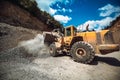 Wheel loader transporting gravel and loading dumper trucks