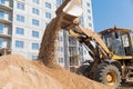 Wheel loader unloading sand from excavator bucket