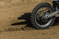 The wheel of a racing motocross motorcycle rides along the race track at high speed, stones and dust fly out from under the wheel Royalty Free Stock Photo